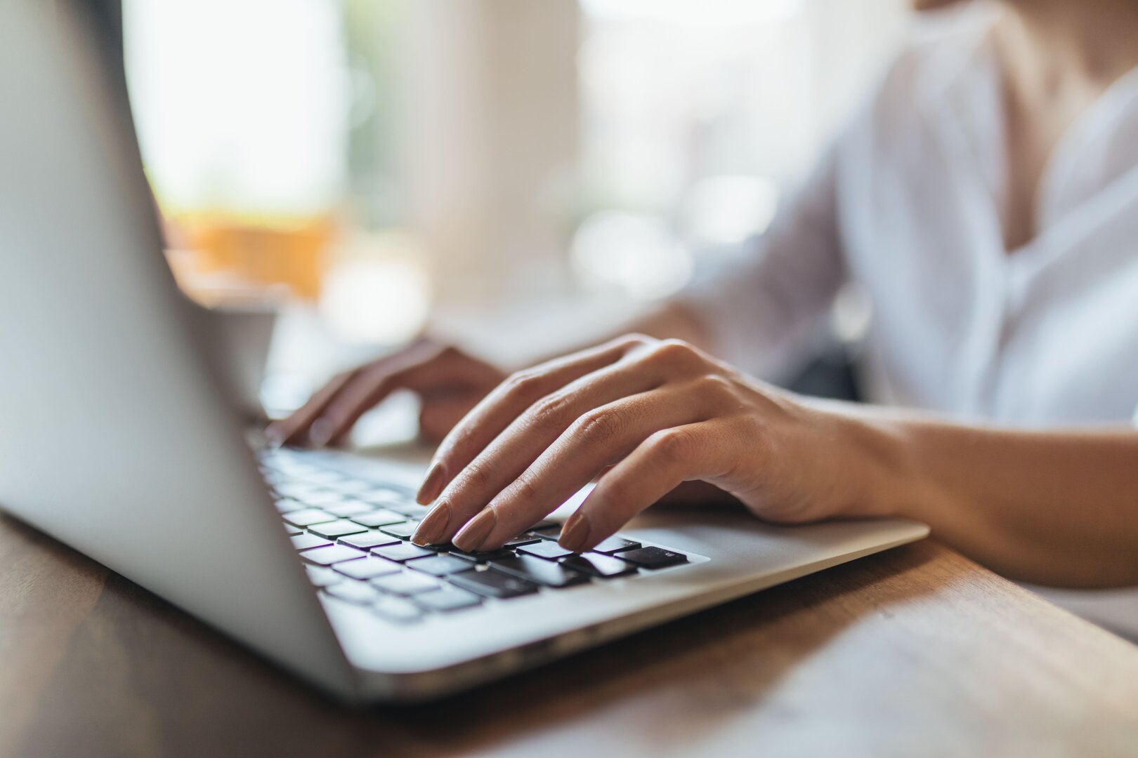 Hände einer Person tippen auf der Tastatur eines Laptops.